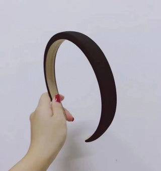 Hand holding dark brown/black wide sponge headband - versatile everyday color, firm arch shape