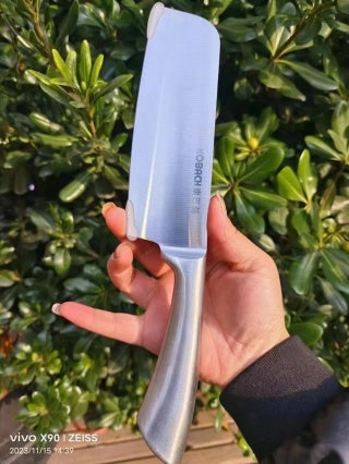 Hand holding 304 stainless steel chef knife outdoors - thin blade, lightweight, full steel one-piece construction