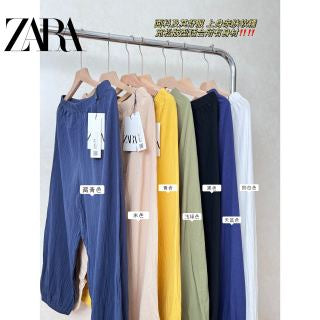 Model wearing navy blue cotton linen carrot pants with white tank top - full length front view